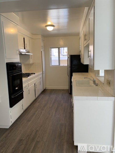 A kitchen with white cabinets and a black fridge.