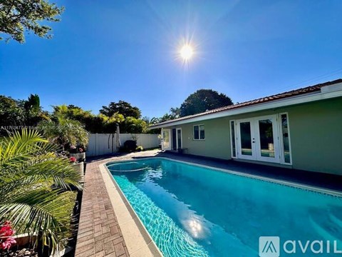 A sunny day at a poolside with a house in the background.