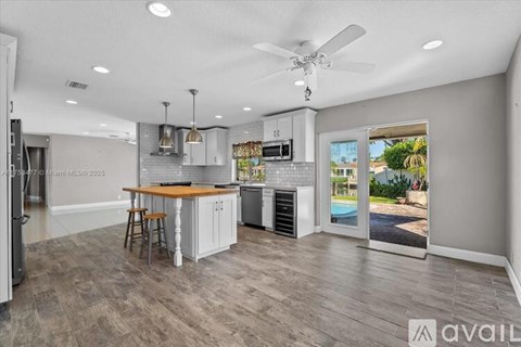 A modern kitchen with a dining table and chairs, a refrigerator, a microwave, and a ceiling fan.