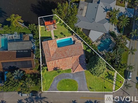 A house with a red roof and a swimming pool is surrounded by a white boundary.