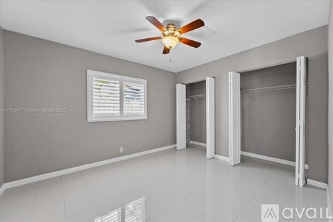 A spacious room with a ceiling fan and a window with blinds.