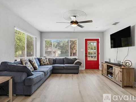 A living room with a grey couch and a red door.