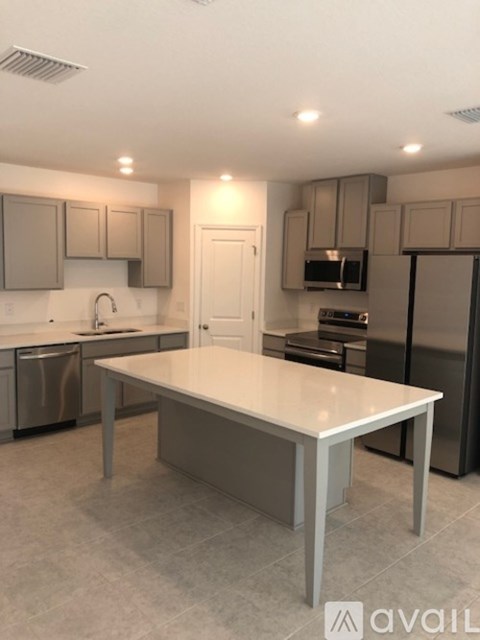 A kitchen with a table in the middle and a refrigerator on the right.