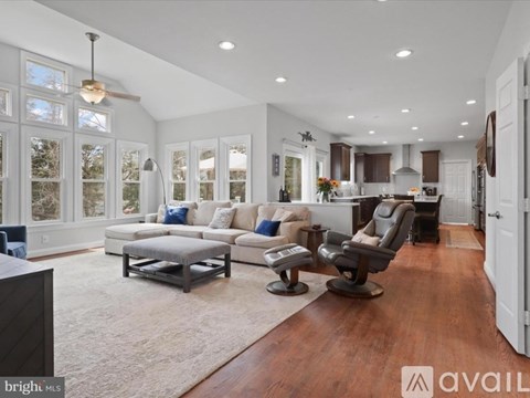 A spacious living room with a grey sofa set and a wooden floor.
