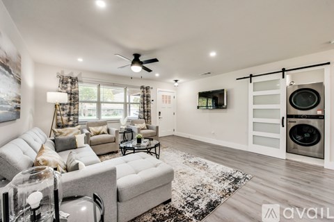 A modern living room with a grey sofa and a black and white rug.