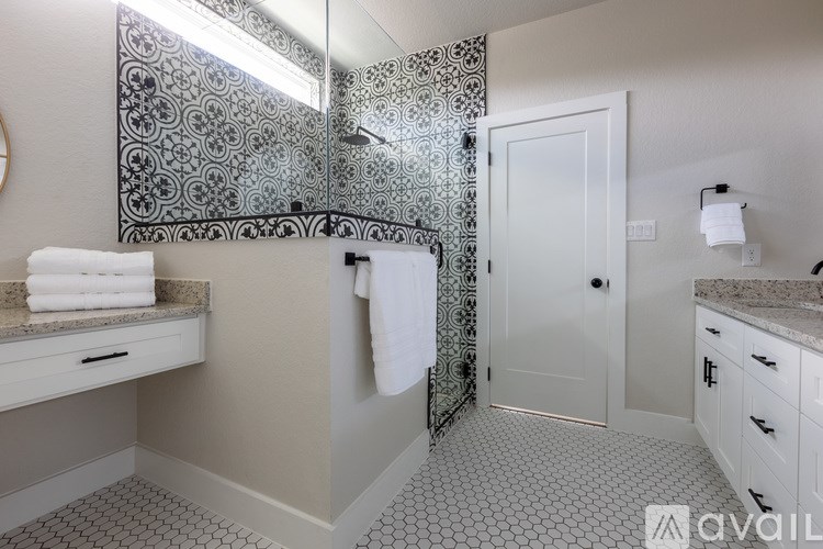 A bathroom with a patterned tile wall and a white door.