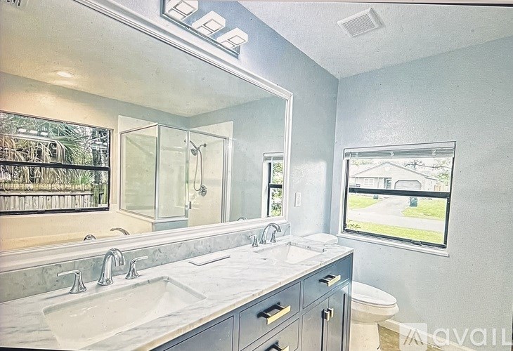 A bathroom with a large mirror, a sink, and a toilet.