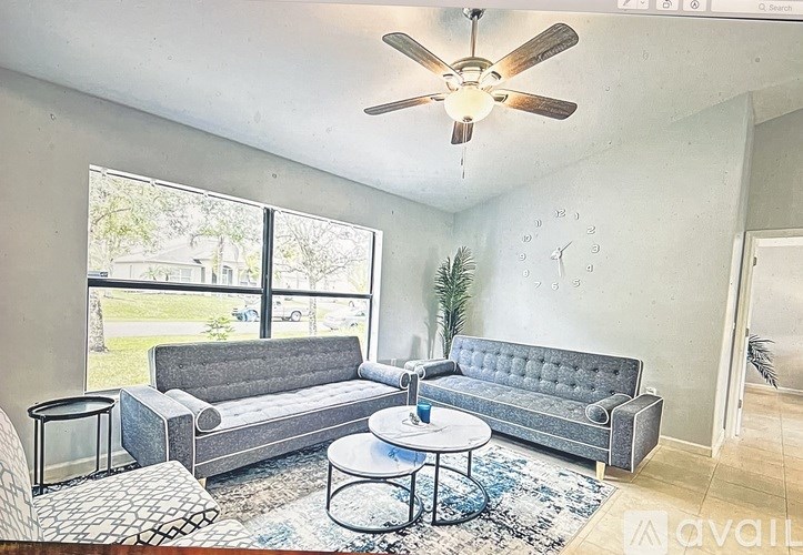 A living room with a grey couch, a small table, and a ceiling fan.