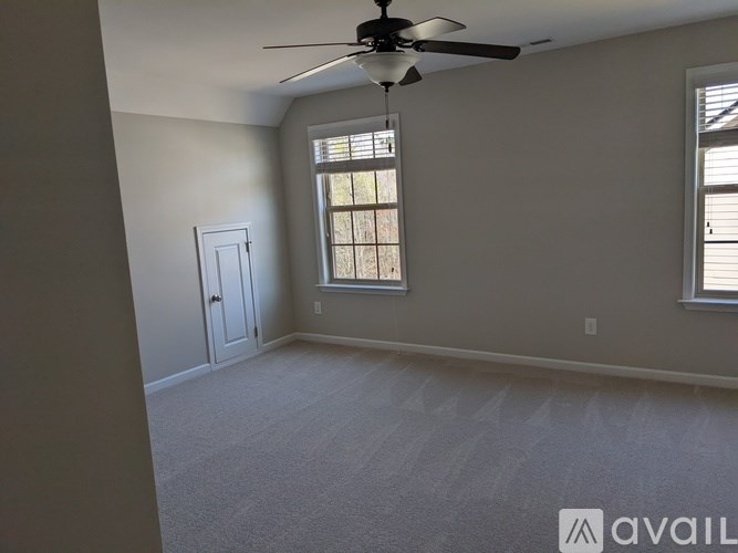 A room with a ceiling fan and two windows.