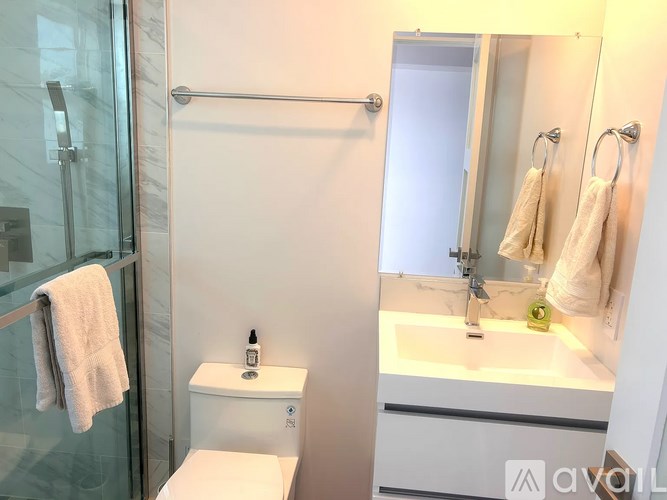 A white toilet with a towel hanging on the glass door of a shower.