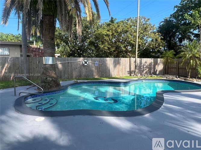 A pool surrounded by a wooden fence and palm trees.