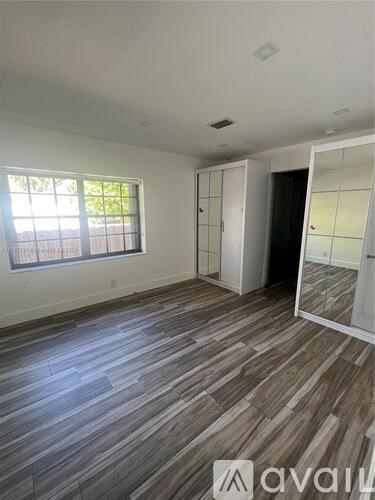 A room with wooden flooring and a large window.