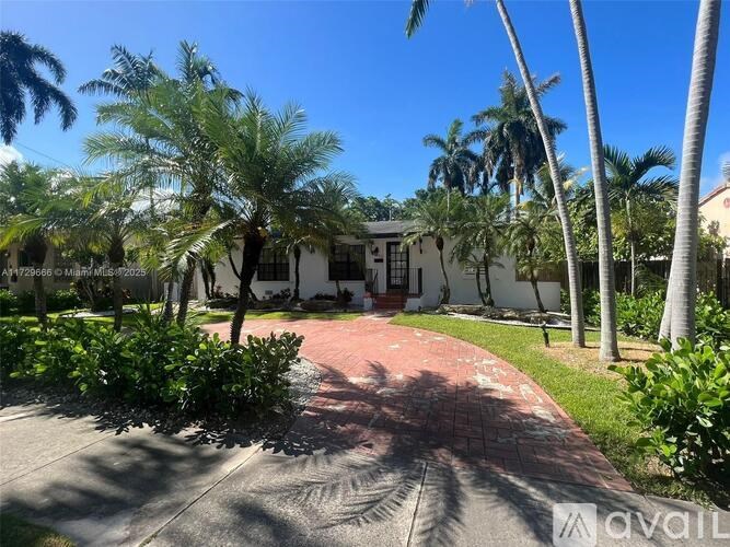 A house with a driveway and palm trees in front.
