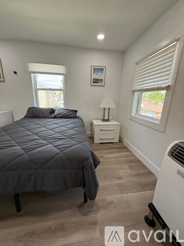 A bedroom with a bed, nightstand, and window.