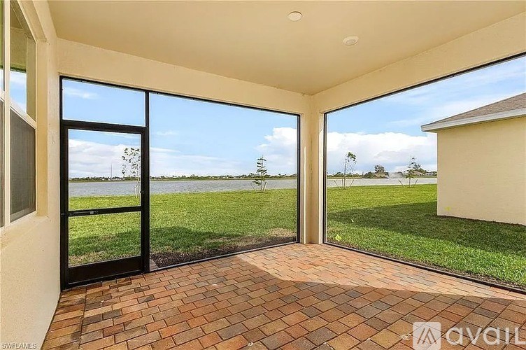 A patio with a brick floor and sliding glass doors leading to a grassy area.