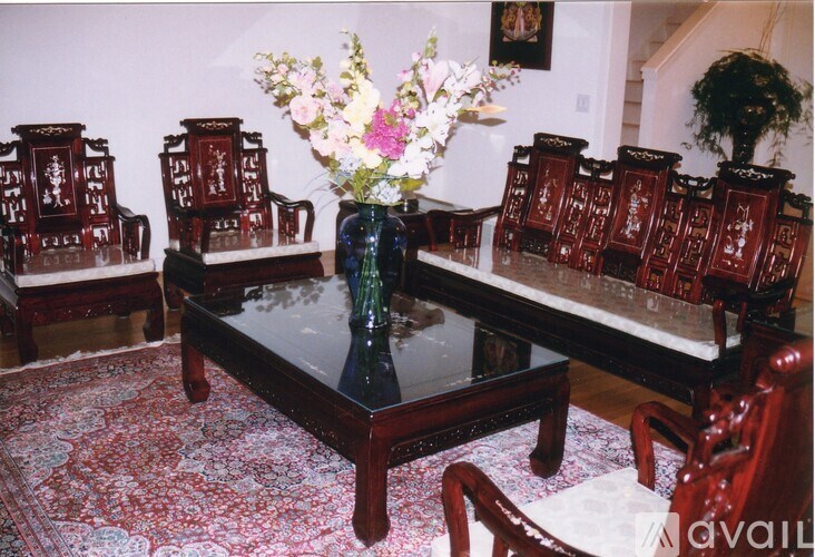 A room with a table, chairs and a vase of flowers.