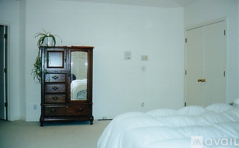 A bedroom with a large bed and a wooden chest of drawers.