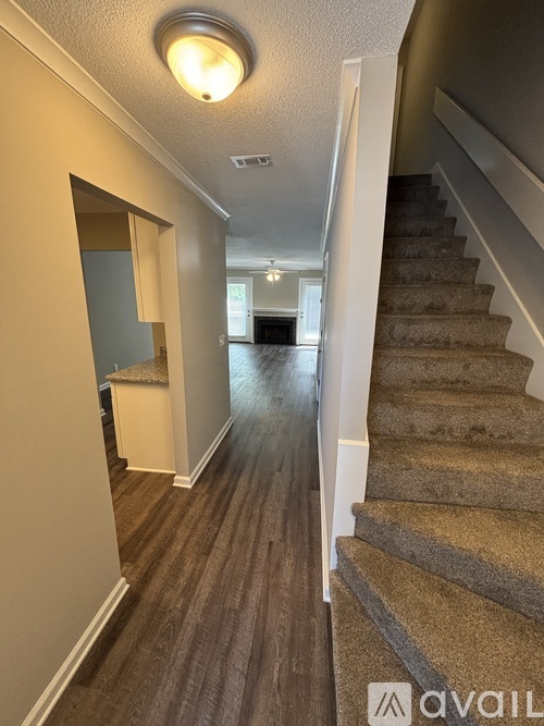 A hallway with a staircase on the right and a door on the left.