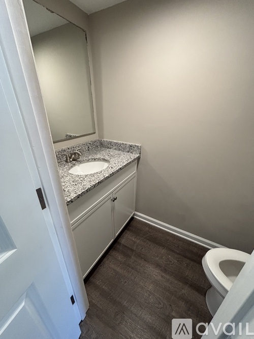 A bathroom with a toilet, sink, and mirror.