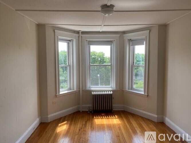 A room with wooden floors and three windows.