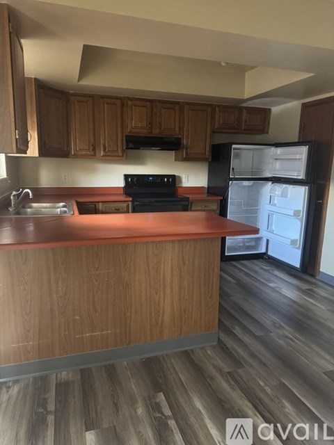 A kitchen with wooden cabinets and a black fridge.
