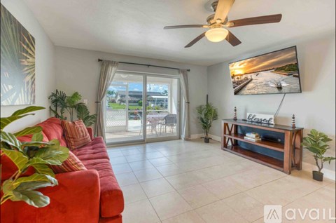A living room with a red sofa, a wooden coffee table, and a flat-screen TV mounted on the wall.