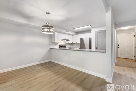A well-lit, empty kitchen with wooden floors and white walls.