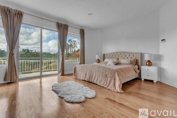A bedroom with a large bed and a view of the outdoors through the sliding glass doors.