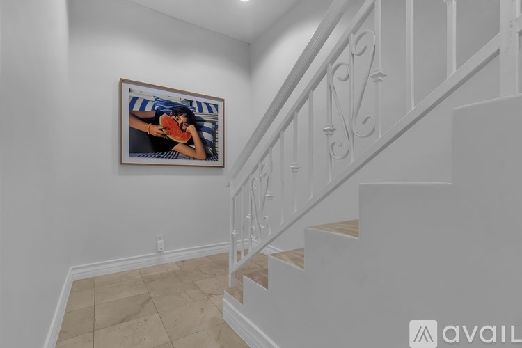 A staircase with a white railing and a framed picture of a woman on the wall.