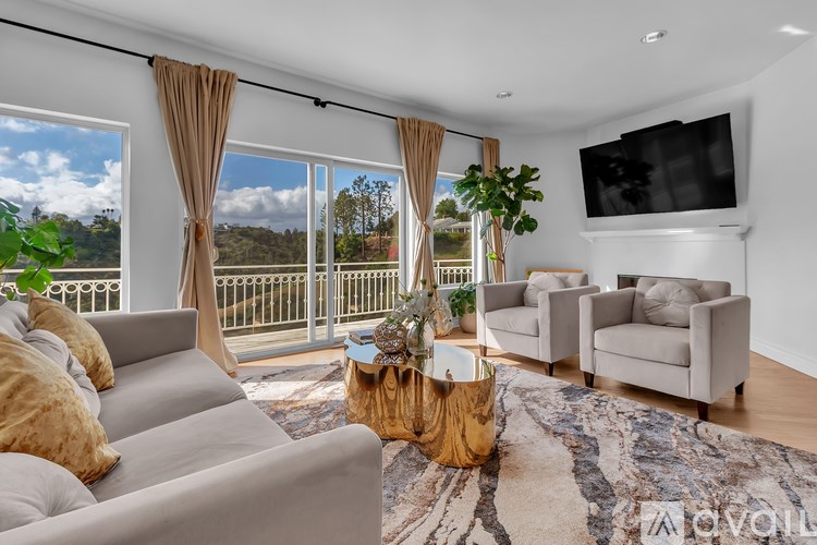 A living room with a grey sofa, a wooden coffee table, and a flat screen TV mounted on the wall.