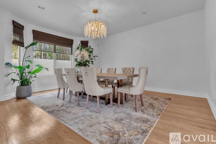 A dining room with a table set for six and a chandelier hanging from the ceiling.
