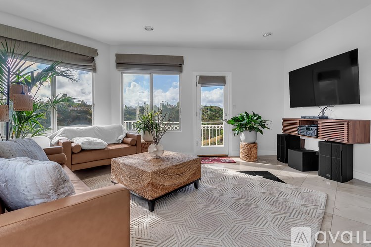 A living room with a brown couch, a wooden coffee table, and a flat screen TV mounted on the wall.