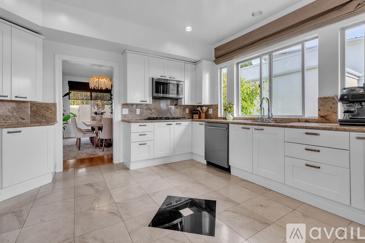 A kitchen with white cabinets and a marble countertop.