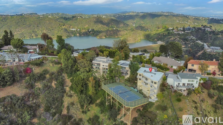 A bird's eye view of a residential area with a lake and a tennis court.