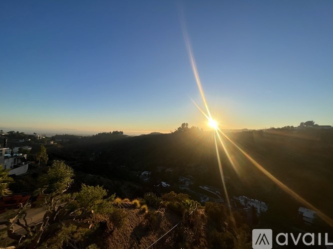The sun is shining brightly over a hilly landscape.