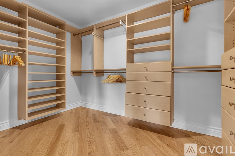 A wooden walk-in closet with drawers and shelves.