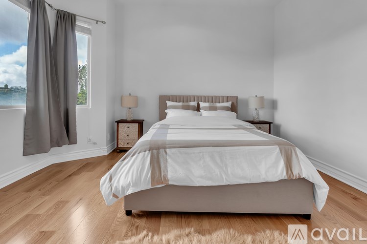 A bedroom with a large bed and a view of the water through the window.