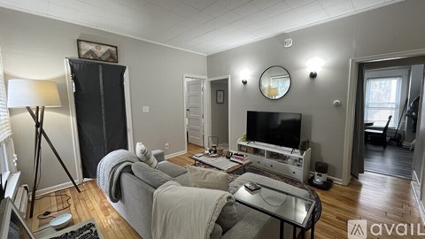 A living room with a grey couch and a black fridge.