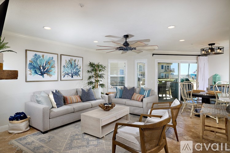 A living room with a grey couch, a wooden chair and a ceiling fan.