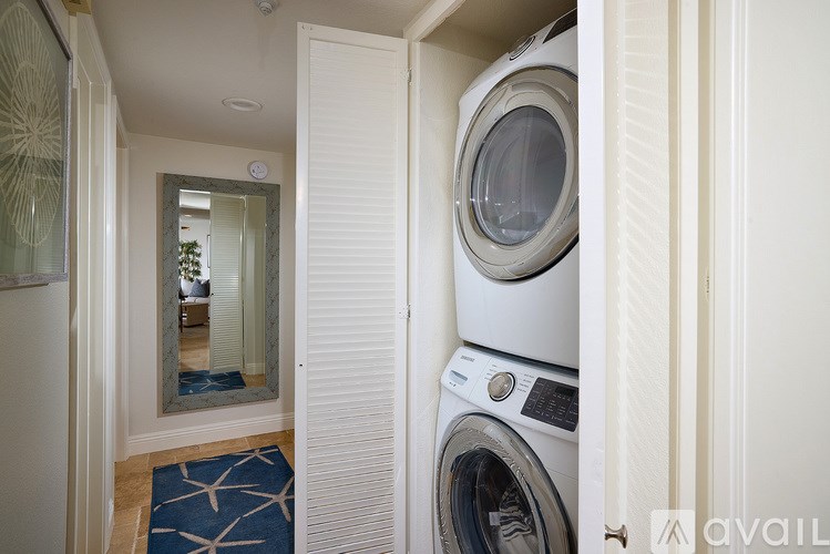 A washing machine and dryer are stacked in a small laundry room.