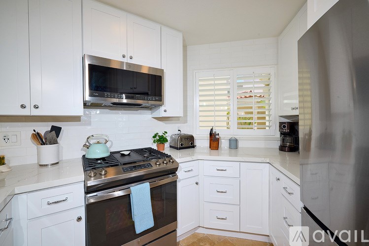 A kitchen with white cabinets and a stove top oven.