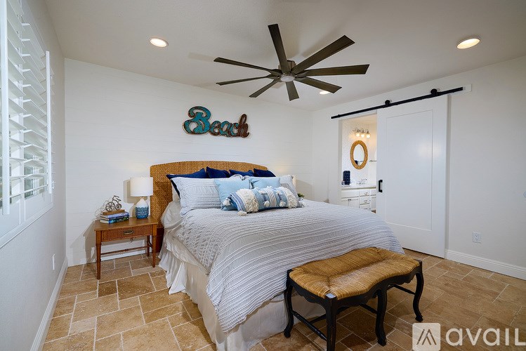 A bedroom with a bed, a bench, and a ceiling fan.