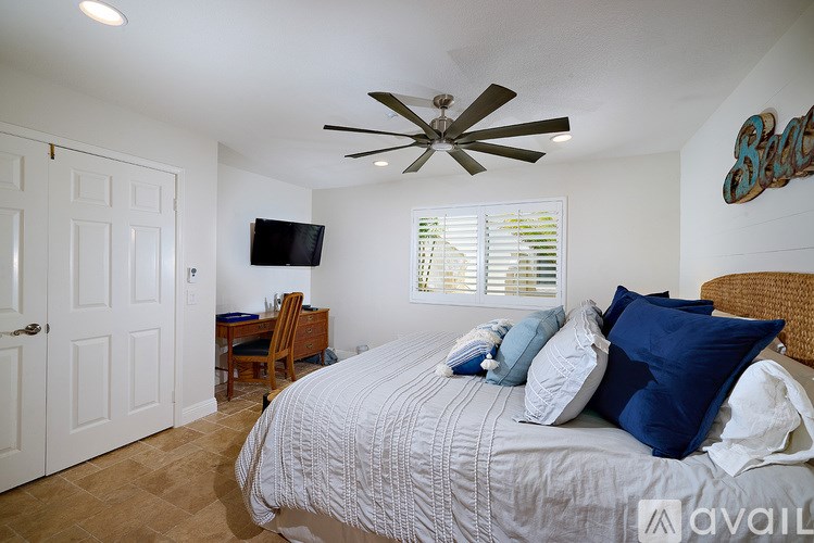 A bedroom with a bed, a ceiling fan, and a television.