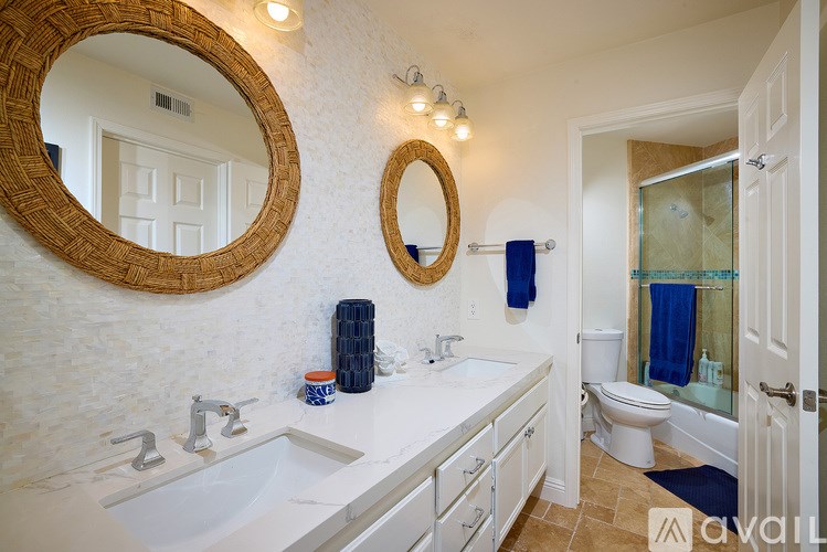 A bathroom with a white counter top and a round mirror above it.