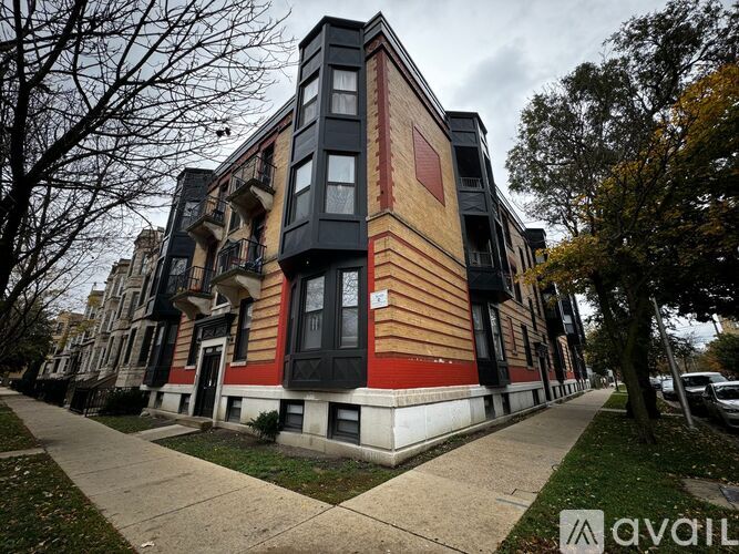 A multi-story building with a black and red facade stands on a sidewalk.