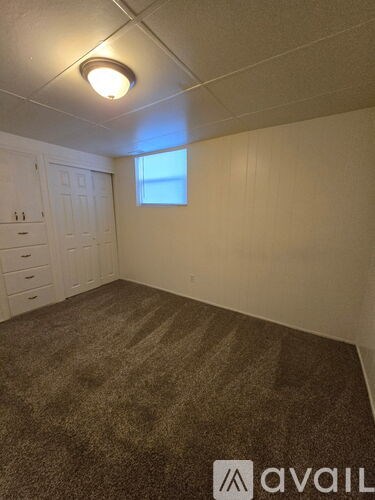 A carpeted room with a window and a white door.