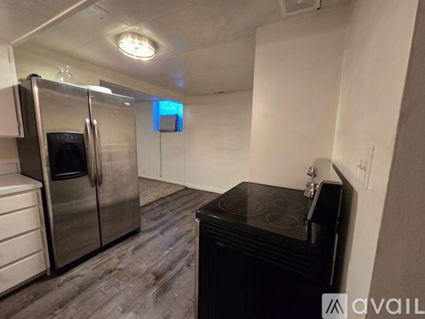 A kitchen with a black stove top oven and a silver refrigerator.
