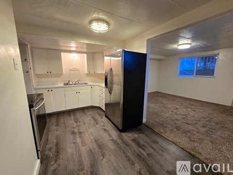 A kitchen with white cabinets and a black fridge is available.