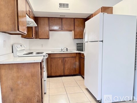 A kitchen with brown cabinets and a white refrigerator.