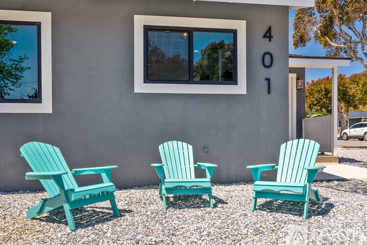 Three blue chairs are placed in front of a house with the number 401 on it.